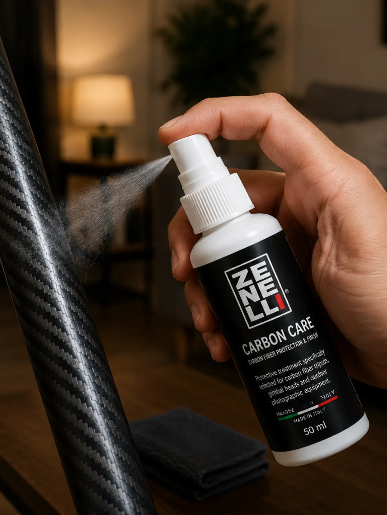 Hand applying Zenelli Carbon Care protective spray on carbon fiber photography equipment