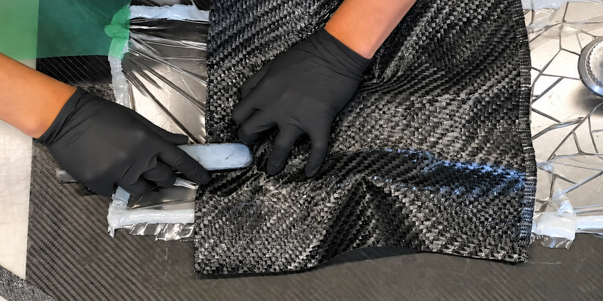 Zenelli craftsmanship in carbon fiber: black-gloved hands carefully lay the fabric by hand to create lightweight composite components